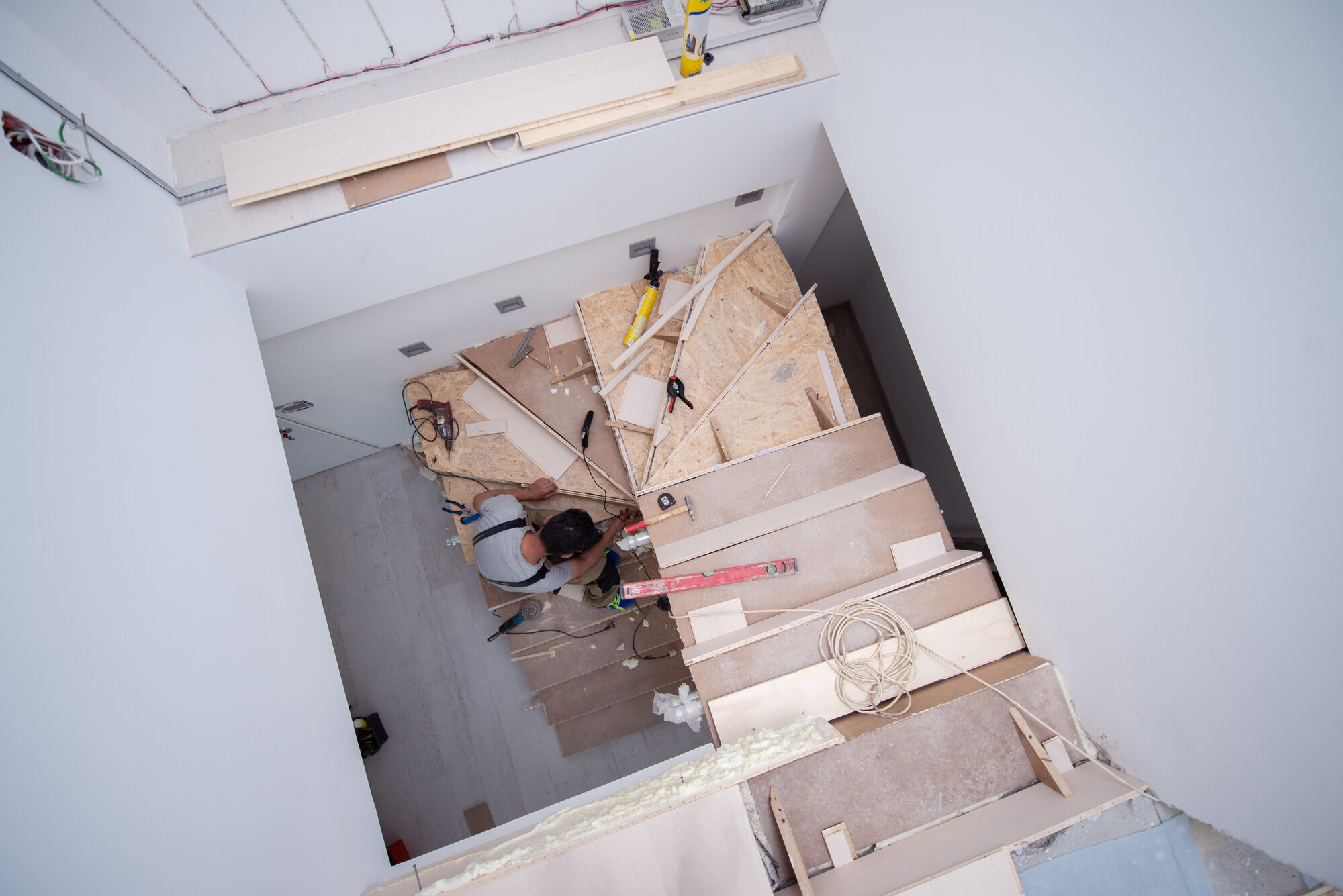 work in progress on stylish interior professional carpenter installing wooden stairs in big modern two level luxury apartment